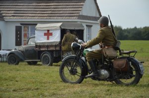 Przed dworem stoi polski ambulans, na pierwszym planie przejeżdża polski motocykl Sokół