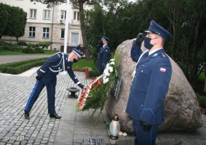 Komendant Główny Policji poprawia szarfę na wieńcu przed obeliskiem upamiętniającym zamordowanych w 1940 roku