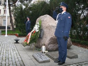 Dwóch funkcjonariuszy Policji stoi po obu stronach obelisku upamiętniającego zamordowanych w 1940 roku