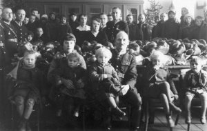 Gwiazdka dla najbiedniejszych dzieci zorganizowana przez Rodzinę Policyjną w Chełmie Lubelskim. Dzieci uczestniczące w gwiazdce. Na stole leżą podarunki wigilijne 1934 rok