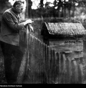 Józef Piłsudski pali papierosa oparty o płot