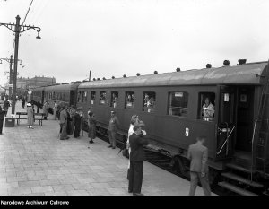 Pociąg osobowy z wagonem Bhuxz (1. z prawej) na peronie. Widoczni pasażerowie, dwóch z nich fotografuje.