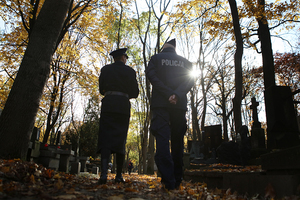 policjanci spacerują po cmentarzu powązkowskim