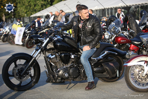 Grupa motocyklistów stoi przy gęsto zaparkowanych motocyklach na PL. Piłsudskiego w Warszawie.