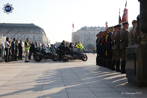 Motocykliści stoją w równych rzędach obok zaparkowanych pojazdów na Pl. Piłsudskiego w Warszawie. Obok nich w rzędzie stoją oficerowie Wojska Polskiego w mundurach reprezentacyjnych.