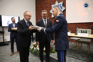 Komendant Główny Policji generał Marek Boroń gratuluje jednemu z uczestników spotkania i wręcza mu pamiątkowa książkę.