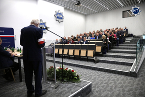 Widok na salę, w której siedzą uczestnicy konferencji. Przy mównicy przemawia jeden z prelegentów.