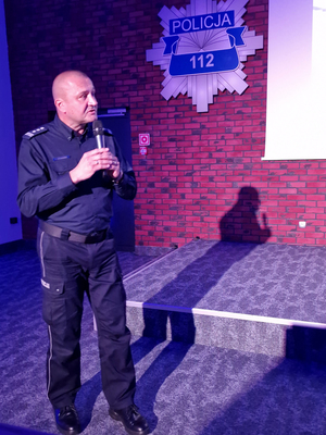 Dyrektor Gabinetu Komendanta Głównego Policji insp. Robert Żółkiewski przemawia do mikrofonu. Za nim na ścianie wisi policyjna gwiazda.