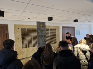 Uczniowie znajdują się w holu KGP, przy pamiątkowej tablicy poświęconej poległym policjantom.