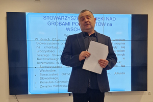 Mężczyzna przemawia do publiczności zebranej w sali Wydziału Edukacji Historycznej. W tle duży ekran z fragmentem raportu dotyczącego działalności Stowarzyszenie Opieki nad Grobami Policjantów na Wchodzie”