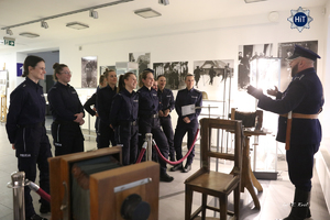 Reprezentantki drużyny w Futsalu słuchają wykładu pracownika Wydziału Edukacji Historycznej ubranego w mundur funkcjonariusza Policji Państwowej, który oprowadza je po wystawie.