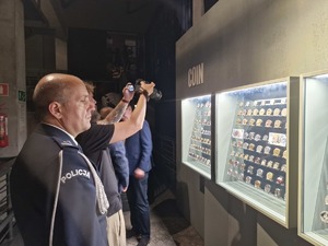 Funkcjonariusz Policji ogląda monety umieszczone w podświetlonych witrynach.