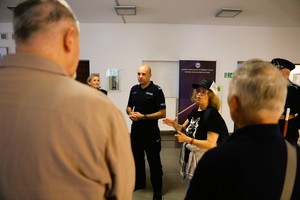 Funkcjonariusz Policji stoi przed grupa osób.