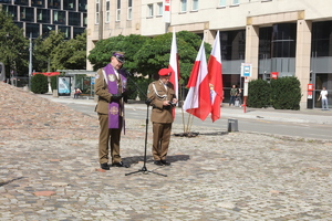 Na skwerze Matki Sybiraczki w Warszawie stoi dwóch oficerów Wojska Polskiego. Jeden z nich ma fioletowa stulę na ramionach.
