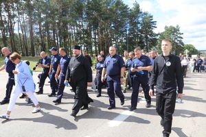 Uczestnicy pielgrzymki, wśród których są funkcjonariusze Policji, idą szosą. Niektórzy z nich niosą prawosławne krzyże.