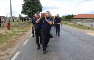 Funkcjonariusze Policji niosą na ramionach wielki drewniany prawosławny krzyż.