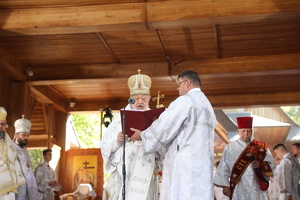 Prawosławny duchowny czyta modlitwę stojąc przed mikrofonem.