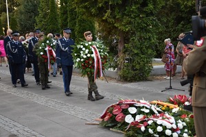 Funkcjonariusze Policji składają wieńce z biało-czerwonych kwiatów pod pomnikiem na Cmentarzu Żołnierzy Poległych 1920 roku.