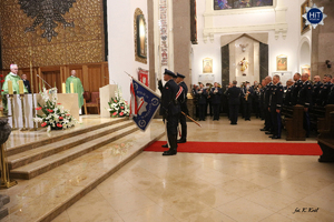 Dwóch funkcjonariuszy Policji stoi przed ołtarzem trzymając sztandar. W tle Reprezentacyjna Orkiestra Policji.