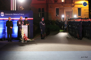 Ksiądz biskup oraz prawosławny duchowny stoją przy mikrofonie na placu przed Komendą Główną policji. Przed nimi  Kampania Reprezentacyjna Policji.