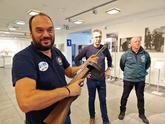 Mężczyzna trzyma w rękach zabytkową długą broń.