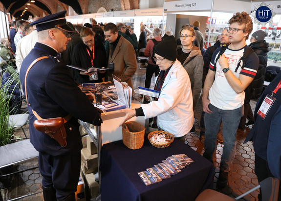 Stoisko Wydziału Edukacji Historycznej, przy którym stoi mężczyzna w mundurze funkcjonariusza Policji Państwowej. Przy stoisku osoby zainteresowane publikacjami prezentowanymi przez Wydział.