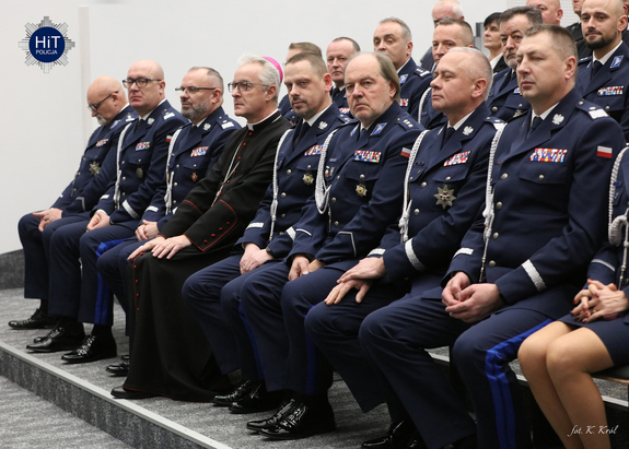 Widok na funkcjonariuszy Policji w mundurach wyjściowych siedzących w pierwszym rzędzie.