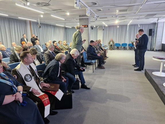 W sali konferencyjnej Instytutu Pamięci Narodowej siedzą zaproszeni goście. Przed nimi stoi dwóch mężczyzn odczytujących przemówienia