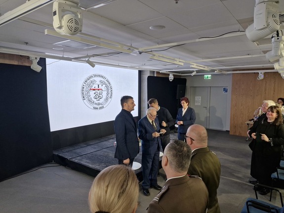 Przed zebraną publicznością stoi grupa osób, wśród których obecny jest Lech Parell -Minister z Urzędu do Spraw Kombatantów i Osób Represjonowanych
