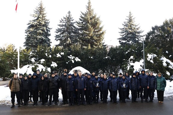 Uczniowie klasy mundurowe pozują do wspólnego zdjęcia na placu przed budynkiem Komendy Głównej Policji. Wśród nich stoi Komendant Główny Policji