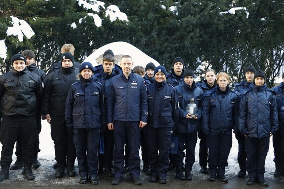 Uczniowie klasy mundurowe pozują do wspólnego zdjęcia na placu przed budynkiem Komendy Głównej Policji. Wśród nich stoi Komendant Główny Policji